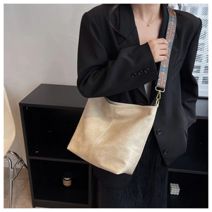 Borsa a spalla beige con ampia tracolla geometrica colorata indossata su un abito nero