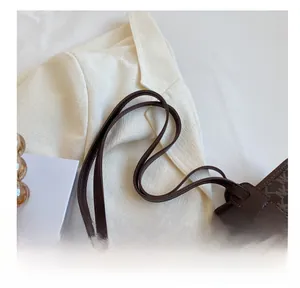 Close-up of brown tote bag featuring NK monogram print and smooth synthetic leather straps
