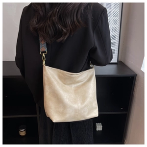 Detail of cream crossbody bag with pebbled leather texture and geometric woven strap