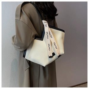 Detailed view of white pleated tote bag with black trim and branded logo strap