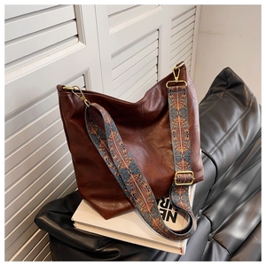 Detail of hobo bag with ethnic print wide strap and textured dark brown leather