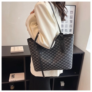 Detail of large tote bag with monogram print and slim leather straps for daily commute
