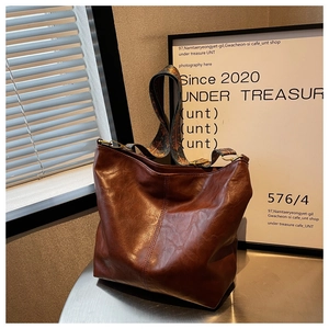 Detail of dark brown leather tote bag with vintage wide patterned shoulder strap