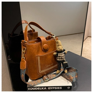 Detail of brown litchi leather bucket bag with retro studs and ethnic geometric strap