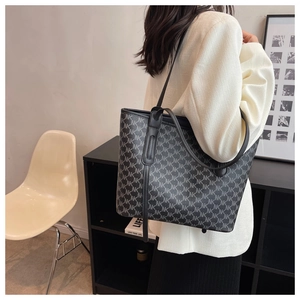 Detail of large tote bag with NK monogram print worn over the shoulder for commute