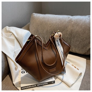 Detail of dark brown pleated PU leather tote bag with a decorative logo ribbon