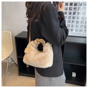 Detail of beige faux fur handbag featuring a twisted leather handle and branding tag