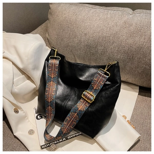 Detail of black soft leather bucket bag with bohemian vintage jacquard woven strap