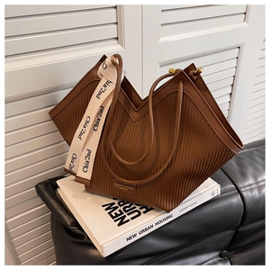 Detailed view of dark brown pleated tote bag featuring woven strap and urban decor