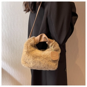 Detail view of khaki faux fur handbag with ruched leather handle and metal logo tag