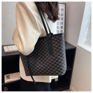 Close-up of large tote bag with NK monogram pattern and sleek black shoulder straps