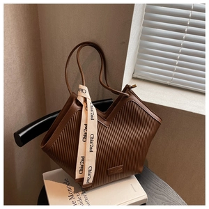 Detail of dark brown pleated PU leather tote bag with V-cut structure and brand ribbon