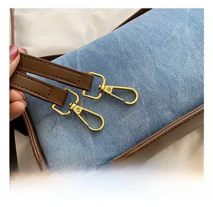 Detail of denim and brown leather stitching with premium gold hardware hooks on bag