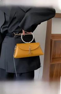 Detail of yellow leather handbag with crystal round handle and metal chain ornament