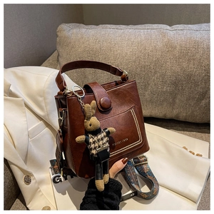 Detail of dark brown leather bucket bag with metal rivets and floral wide strap