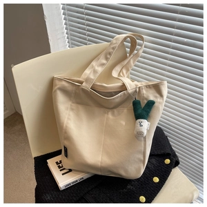 Detail of canvas tote bag with contrast stitching and plush green onion pendant