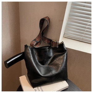 Detail of black bucket bag with a retro floral wide strap and gold metal hardware