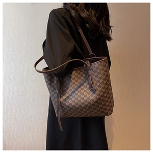 Close-up of large brown monogram tote bag with leather straps and logo pattern