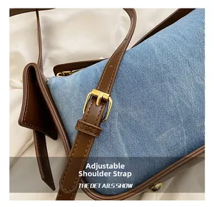 Detailed close-up of adjustable leather shoulder strap and blue denim fabric of the bag