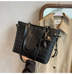 Detailansicht der schwarzen Stepp-Tote-Bag mit Goldnieten und einem Bären-Anhänger