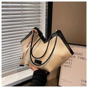 Detail view of cream PU pleated tote bag with black trim and wide jacquard logo strap