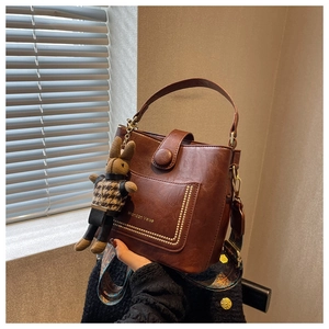 Detail of brown leather bucket bag with gold studs and ethnic style crossbody strap