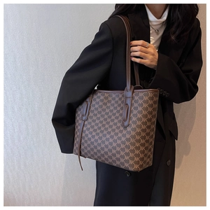 Detailed close-up of large monogram tote bag with brown leather trim and shoulder straps