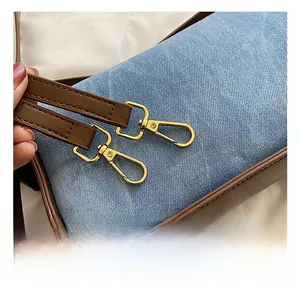 Detail of high-quality golden metal hooks on a blue denim and brown leather shoulder bag