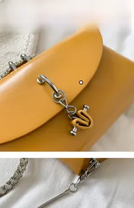 Close-up of yellow leather handbag with silver chain and heart-shaped pendant detail