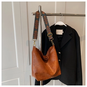 Detail of caramel brown tote bag with wide vintage patterned woven shoulder strap