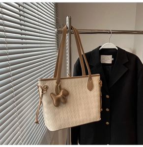 Details der beige gesteppten Tragetasche mit braunem Lederbesatz und Welpen-Anhänger