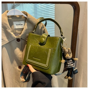 Detail of avocado green bucket bag with contrast stitching and floral strap