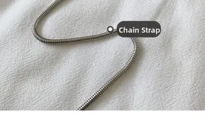 Detailed macro shot of a glossy silver metal snake bone chain shoulder strap for bags