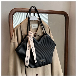 Detail of black pleated tote bag with fashion letter strap and stylish leather patch