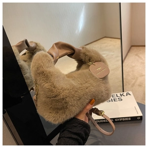 Détail d'un sac à main en peluche chameau avec poignée en cuir et chaîne dorée