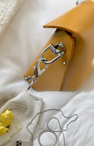 Macro detail of silver hardware and chain strap on a mustard yellow leather crossbody bag