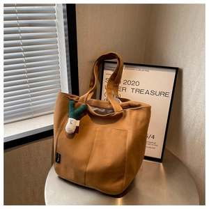 Detailed shot of brown canvas tote bag with a unique leek plush charm on a metal table