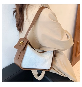 Detail of white textured fabric and brown leather shoulder bag with gold metal buckle