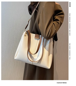 Side view of large cream and brown tote bag styled with olive green winter coat