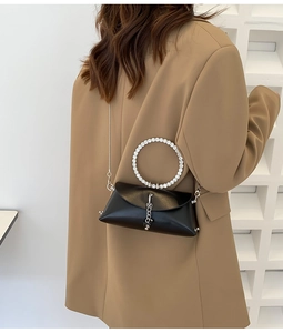 Detail of black leather bag with rhinestone circular handle and silver chain strap