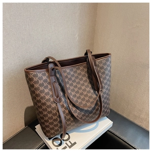 Detailed close-up of dark brown monogram tote bag with faux leather handles and piping