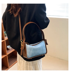 Detail showing the brown leather strap and side triangle fold of the blue tote bag