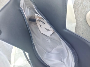 Detail view of the black PU leather tote interior with herringbone lining and canvas strap