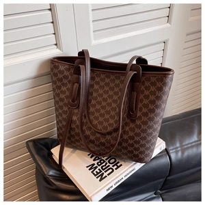 Detailed close-up of brown monogram tote bag with leather straps on aesthetic props