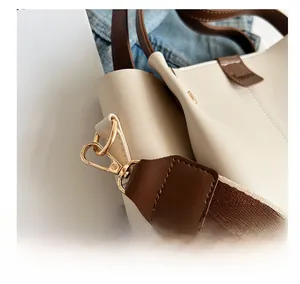 Detail of golden metal hooks and dual-tone wide shoulder strap on tote bag
