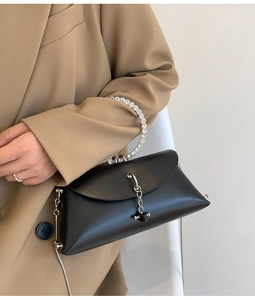 Detail of elegant black matte leather handbag with rhinestone handle on model