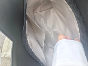 Internal view of black tote bag showing chevron lining, inner pocket and metal zipper
