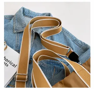 Detalle de correa ancha de nailon caqui con hebilla plateada sobre denim