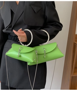 Detail of bright green leather bag with rhinestone handle and silver chain strap