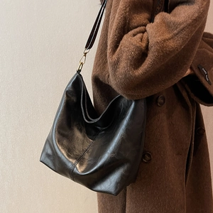 Retro black leather hobo bag with adjustable strap worn on a stylish wool coat